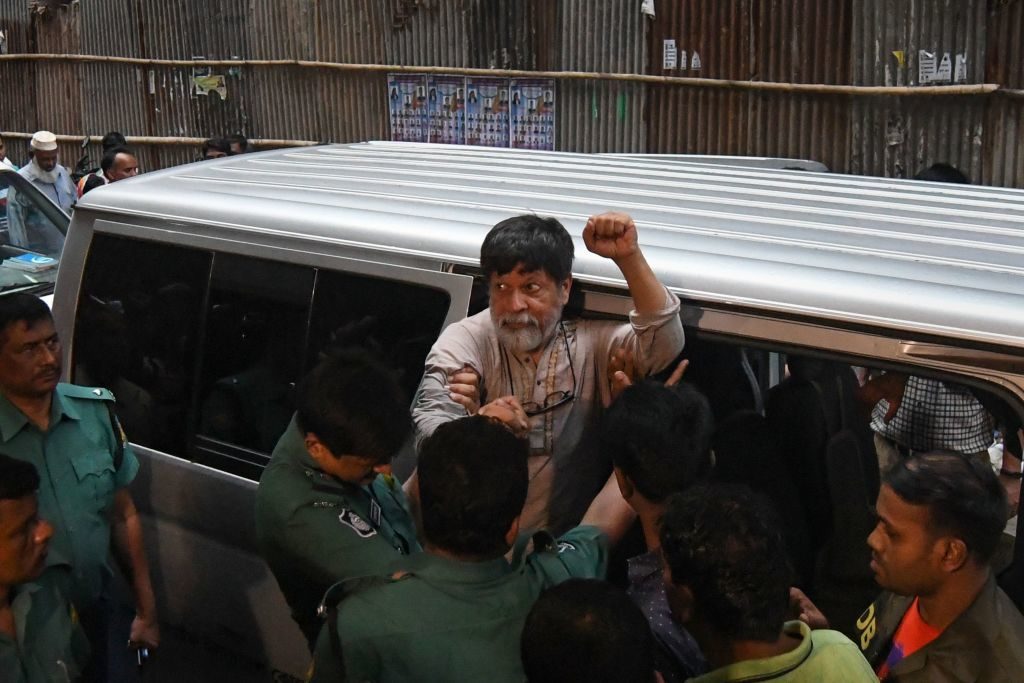Activist and photographer Shahidul Alam gestures as he is removed from a vehicle by policemen for an appearance in a court, in Dhaka on August 6, 2018. Photo courtesy Munir Uz Zaman/AFP/Getty Images.