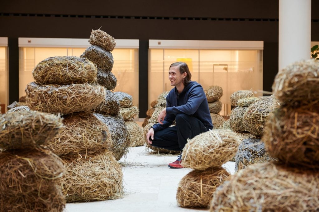 Artist Augustas Serapinas with his installation Mudmen (2020), presented by Emalin as a part of Art Basel's Parcours section. Courtesy of Emalin.