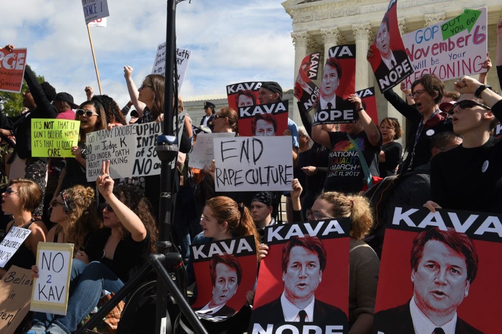 Activist demonstrate against US Supreme Court nominee Brett Kavanaugh in front of the court in Washington, DC, on September 28, 2018. Many hold Tracie Ching's <em>Kavanope</em> poster. Photo by Eric Baradat/AFP/Getty Images)