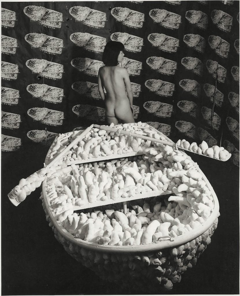 Yayoi Kusama posing with "Aggregation- One Thousand Boats Show" (1963), at Gertrude Stein Gallery, New York. ©Yayoi Kusama and Yayoi Kusama Studios Inc.