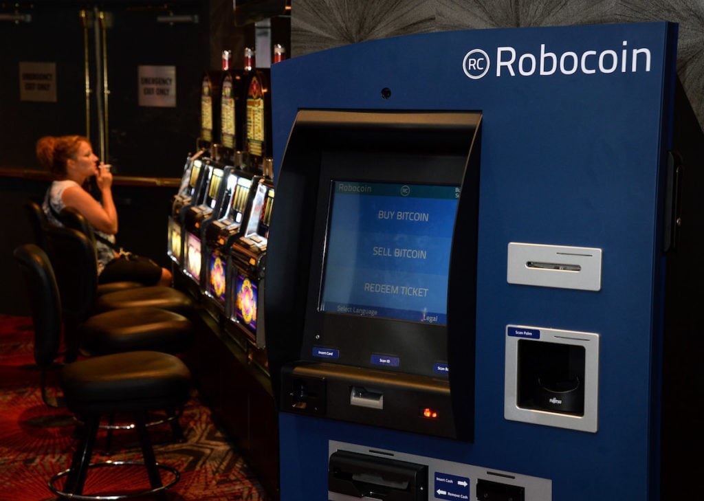 A gambler plays a slot machine near a Robocoin ATM that accepts Bitcoin at the D Las Vegas on May 24, 2014 in Las Vegas, Nevada. Robocoin shut down two years later, in 2016. Photo by Ethan Miller/Getty Images.