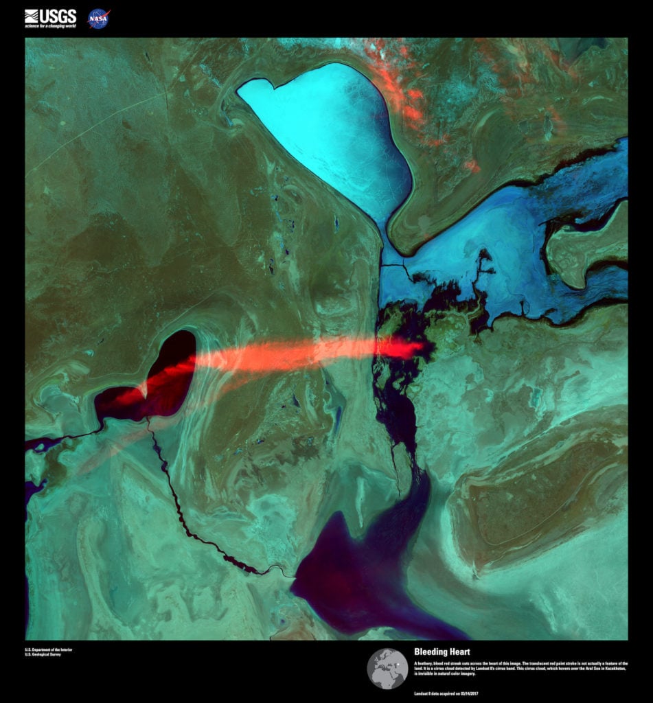 Landsat 8, <em>Bleeding Heart</em>. A feathery, blood red streak cuts across the heart of this image. The translucent red paint stroke is not actually a feature of the land. It is a cirrus cloud detected by Landsat 8’s cirrus band. This cirrus cloud, which hovers over the Aral Sea in Kazakhstan, is invisible in natural color imagery. Image courtesy of US Geological Survey/NASA.