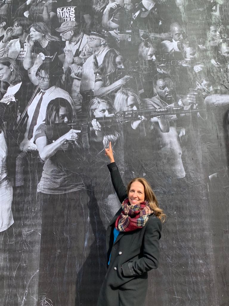 Dianna Muller points to herself in JR's "Guns in America" mural. Photo by Sarah Cascone.