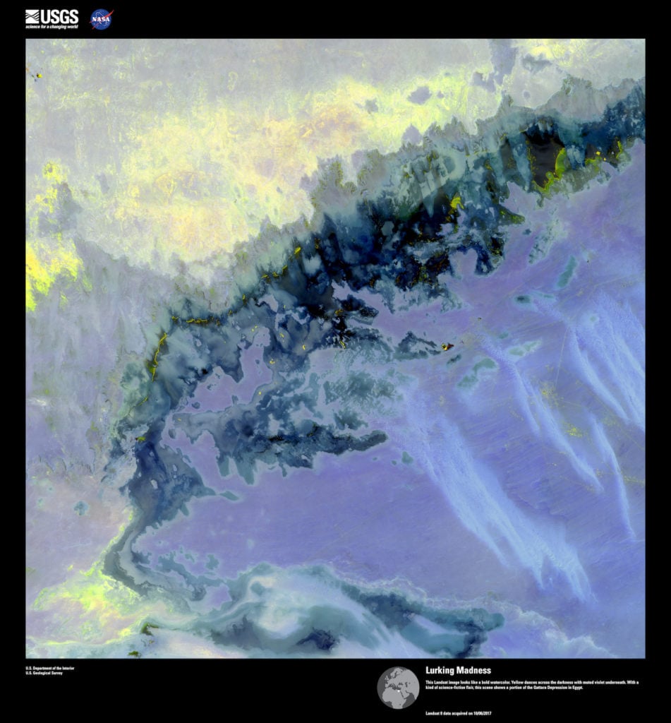 Landsat 8, <em>Lurking Madness</em>. This Landsat image looks like a bold watercolor. Yellow dances across the darkness with muted violet underneath. With a kind of science-fiction flair, this scene shows a portion of the Qattara Depression in Egypt. Image courtesy of US Geological Survey/NASA.