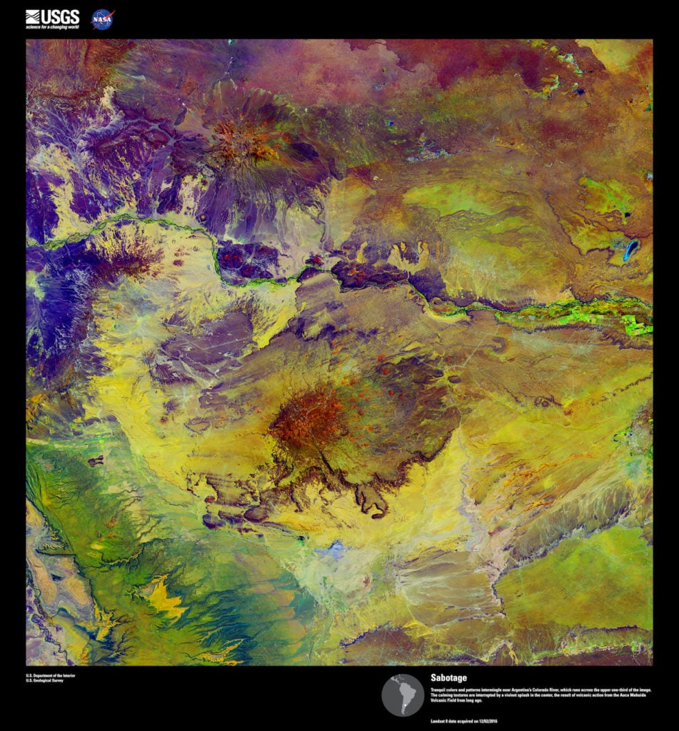 Landsat 8, <em>Sabotage</em>. Tranquil colors and patterns intermingle near Argentina’s Colorado River, which runs across the upper one-third of the image. The calming textures are interrupted by a violent splash in the center, the result of volcanic action from the Auca Mahuida Volcanic Field from long ago. Image courtesy of US Geological Survey/NASA.