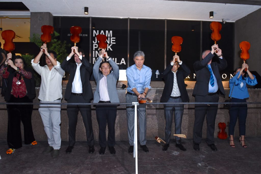 U.S. Ambassador to the Philippines Sung Kim leads a performance of Nam June Paik’s piece One for Violin at the opening of “Nam June Paik in Manila” at León Gallery International. L-R: Curator Lisa G. Nakpil, collector Marcel Crespo, Nick Simunovic, Ken Hakuta, H.E Amb. Kim, Jaime Ponce de León, Jon Huffman, and Lina Juntilla. Courtesy of León Gallery International.
