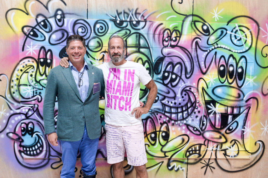 Adam Lindemann with Kenny Scharf in front of Scharf's live painting made during the Art of Blockchains luncheon. PHOTO CREDIT: Madison McGaw/BFA.com.