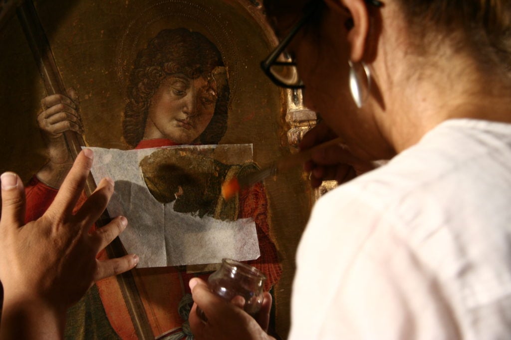 Daniela Storti during the cleaning of Bartolomeo Vivarini's <em>Triptych depicting Madonna with Child, Saint George and Saint Augustine</em>. Photo courtesy of Studio Merlini Storti. 