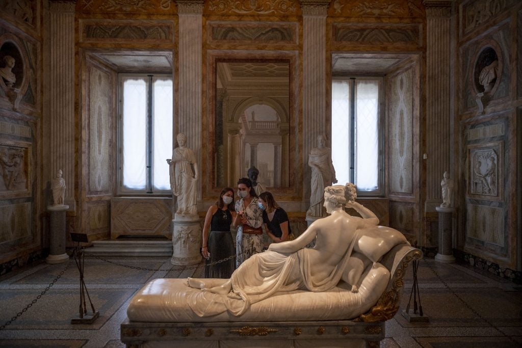 People wearing a protective masks observe the sculpture <em>Paolina Borghese Bonaparte</em> by Antonio Canova, at the Galleria Borghese in Rome after two months of closure during lockdown. Photo by Antonio Masiello/Getty Images.