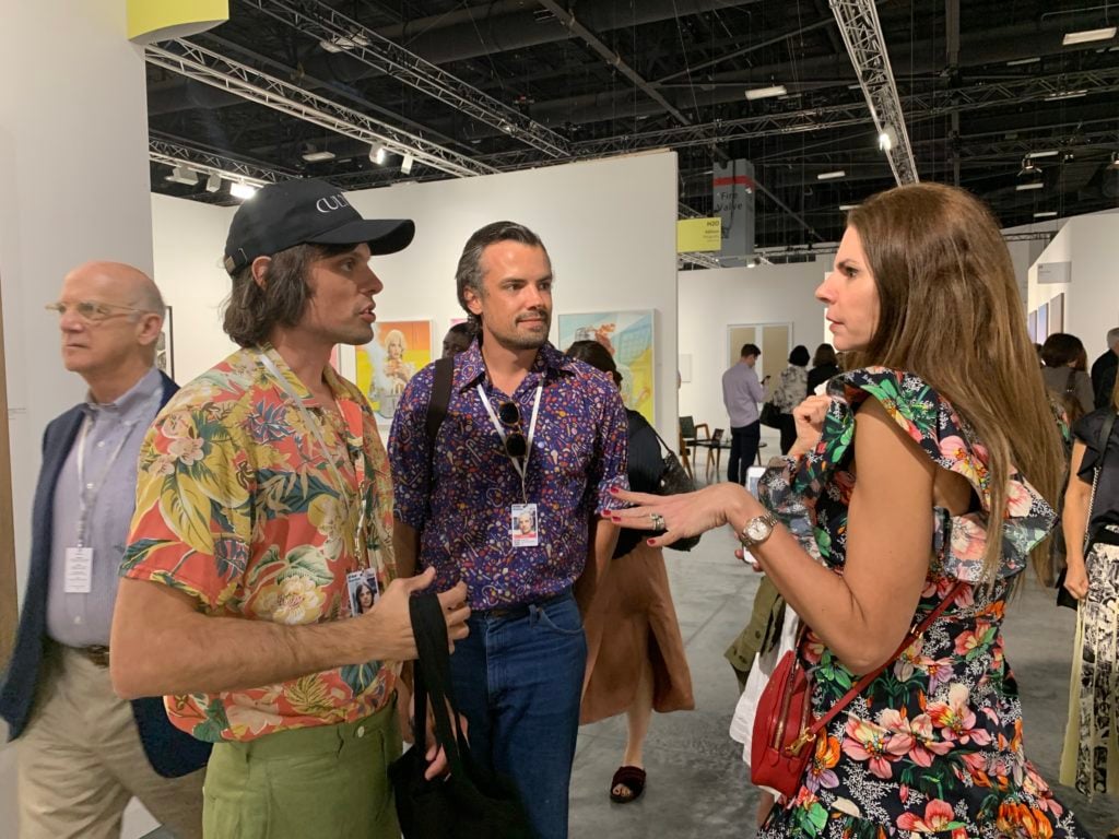 Collector Maria Brito stops to say hello to the Haas Brothers at Art Basel in Miami Beach. Photo by Sarah Cascone. 