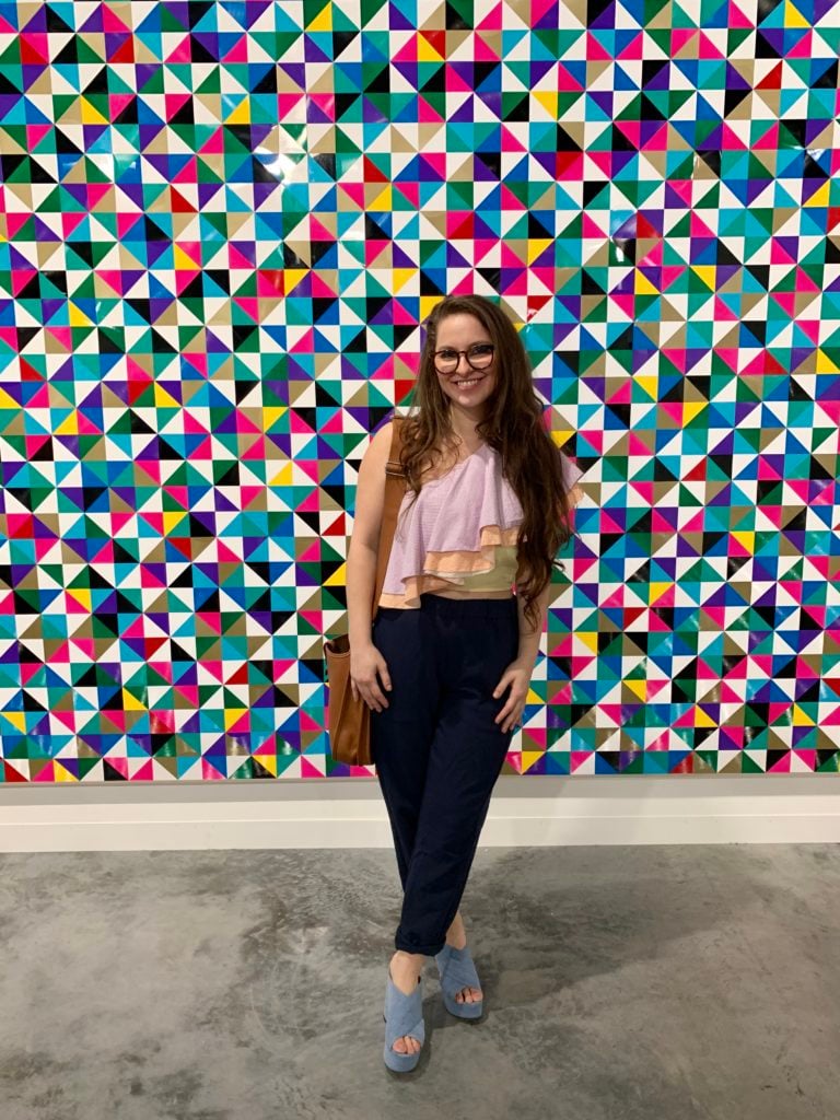 Molly Krause with a painting by Gregor Hildebrandt at Art Basel Miami Beach. Photo by Sarah Cascone. 