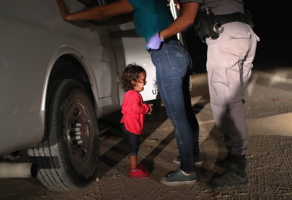 A two-year-old Honduran asylum seeker cries as her mother is searched and detained near the U.S.-Mexico border on June 12, 2018 in McAllen, Texas. Photo by John Moore/Getty Images.