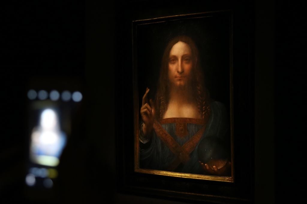  A visitor takes a photo of Leonardo da Vinci's <em>Salvator Mundi</em> painting at the Christie's in New York during its final day of viewing in New York, United States on November 15, 2017. Photo by Mohammed Elshamy/Anadolu Agency/Getty Images.