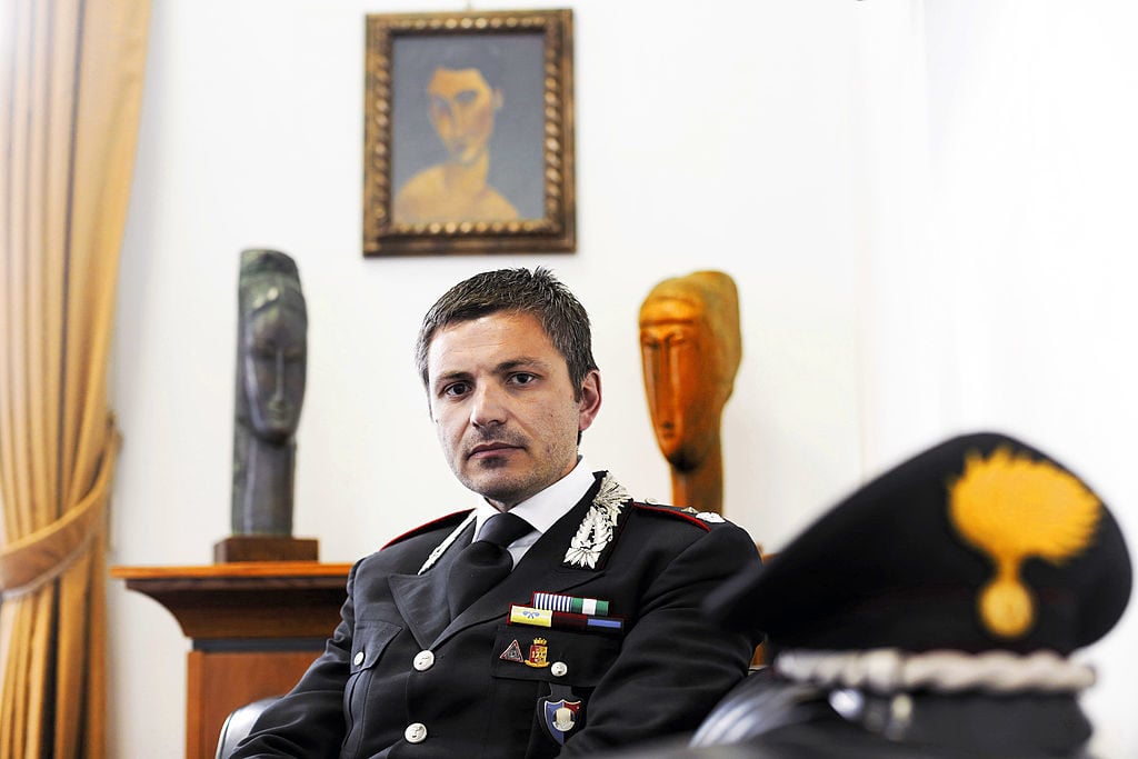 A Carabinieri from the Italian art squad poses in front of fake Modigliani works in 2013. Photo by Franco Origlia/Getty Images.