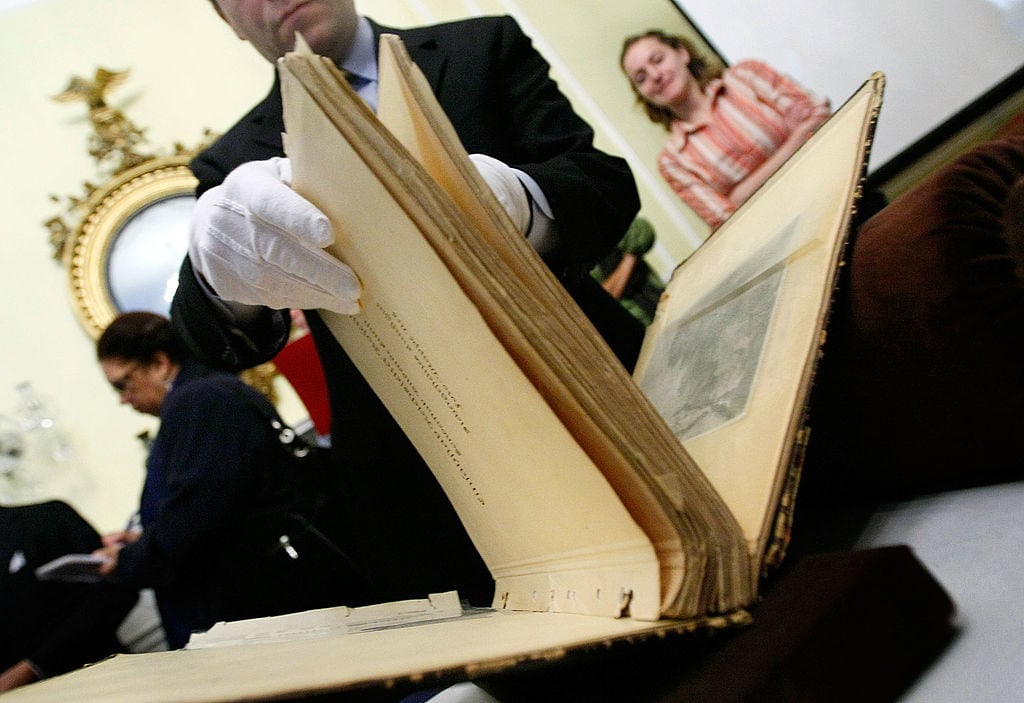 A conservator from the French national archives shows two leather bound photo albums documenting art that was looted by Nazi forces during the Second World War. Photo by Win McNamee/Getty Images.