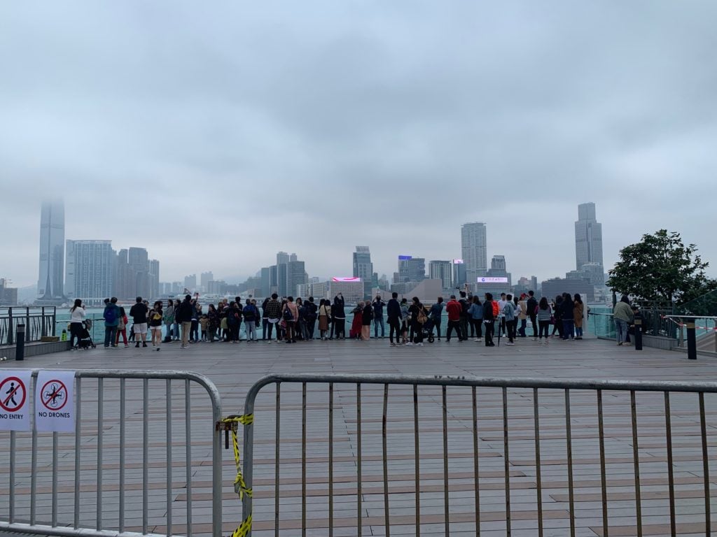 A carefully crowd-controlled batch of visitors huddle to take their photos of "KAWS: Holiday" in Hong Kong. Photo: Julia Halperin.