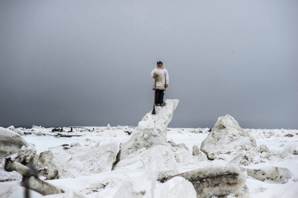 Point Hope, Alaska, USA, May 2018. © Kadir van Lohuizen – NOOR for Fondation Carmignac. Gordon Omnik stands on watch to spot bowhead whales. The local Inuit community is allowed to catch 10 of them each year. Normally, the hunting starts when the sea ice breaks in the spring : the whales migrating up north use the channels to come up to breathe. If the ice melts, the whales can swim around with more ease, which makes them much harder to hunt.