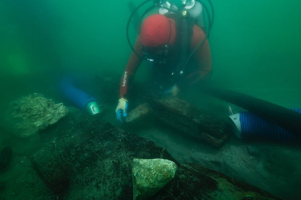 An archaeologist inspects the keel of a shipwreck discovered in the waters around the sunken port-city of Thonis-Heracleion. Photo courtesy of Christoph Gerigk/Franck Goddio/Hilti Foundation