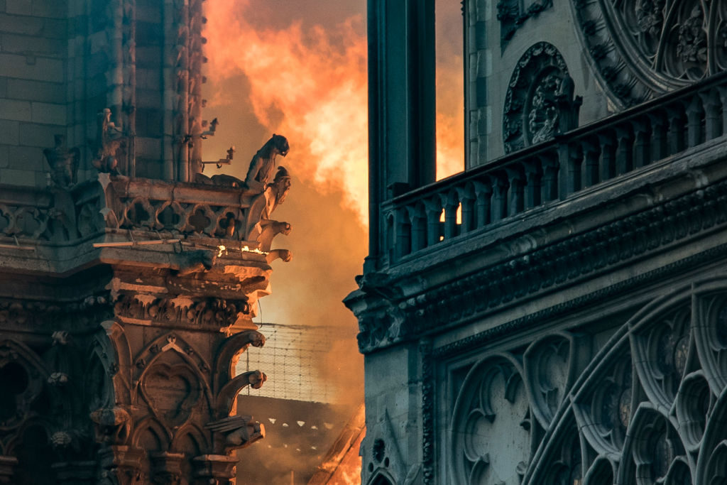 Flames and smoke billow around the gargoyles decorating the roof and sides of the Notre-Dame Cathedral in Paris on April 15, 2019. Photo by Thomas Sansom/AFP/Getty Images.