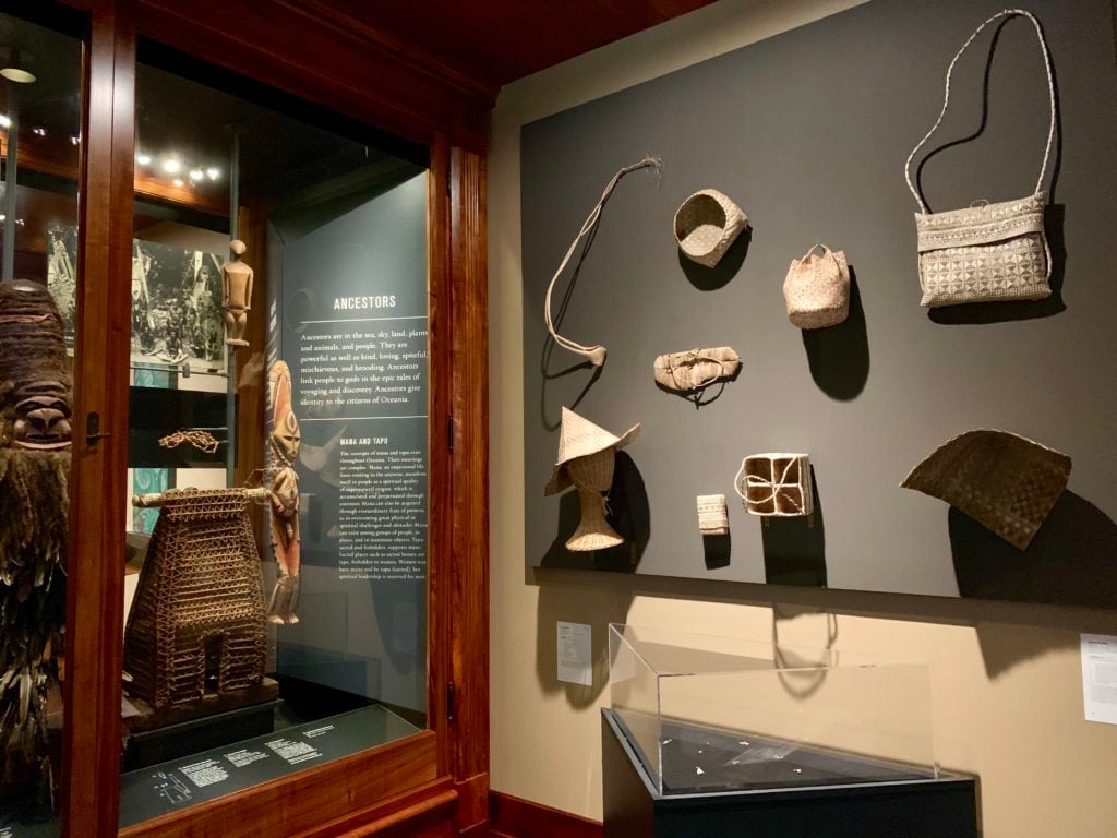 Native Hawaiian artifacts, left, and James Bamaba's contemporary interpretations of traditional woven pandanus leaf objects, right at the Bernice Pauahi Bishop Museum – Hawai’i State Museum for the Honolulu Biennial. Photo by Sarah Cascone. 