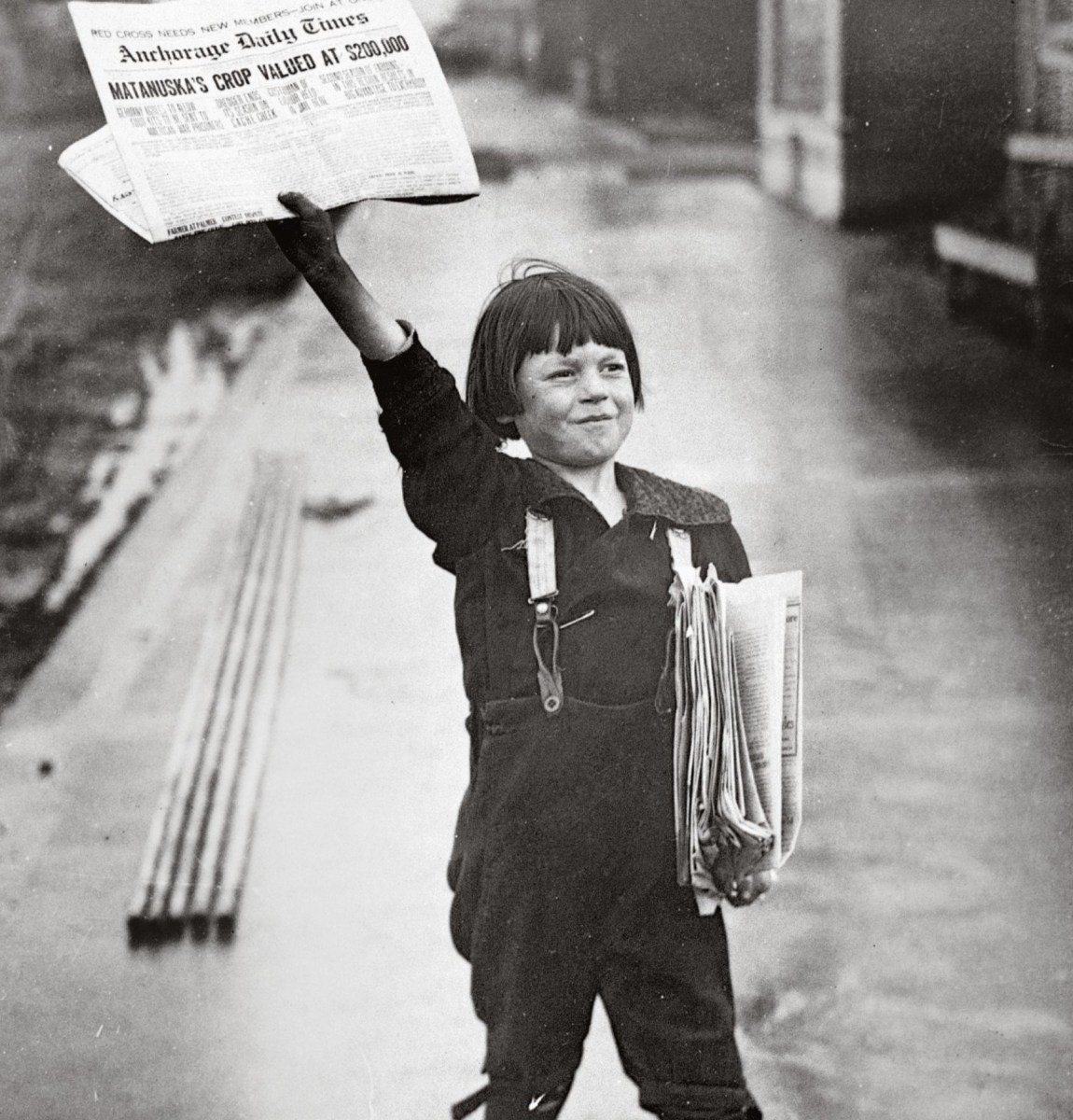 A newsboy holds up a copy of the "Anchorage Daily Times" in the early 20th century. Courtesy of the Library of Congress.