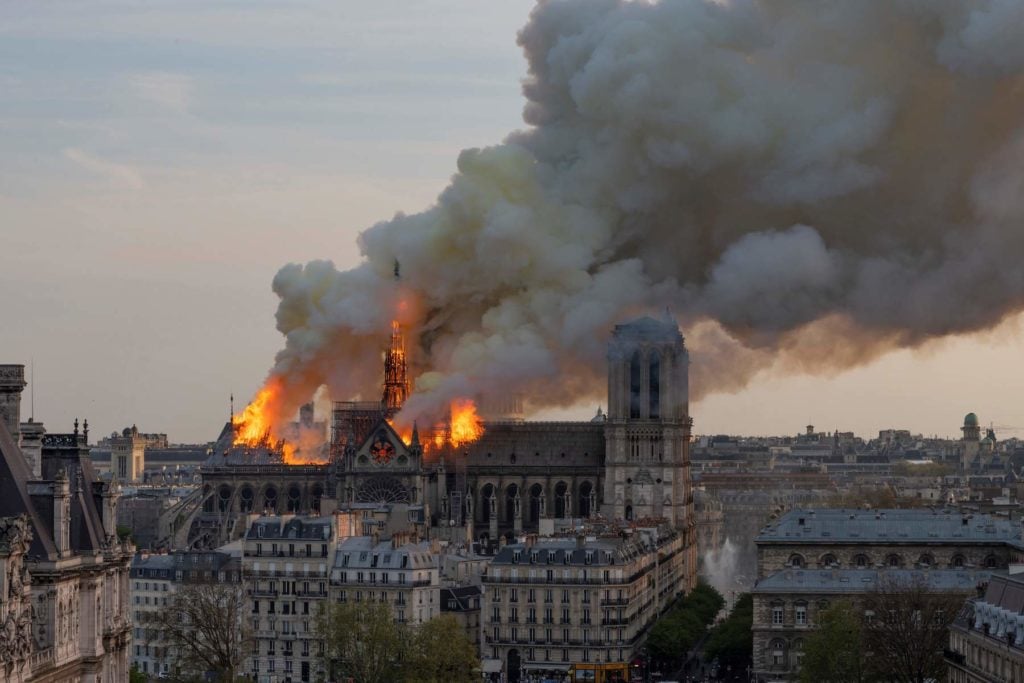 Smoke billows as flames burn through the roof of the Notre-Dame de Paris Cathedral on April 15, 2019, in the French capital Paris. Photo courtesy Fabien Barrau/AFP/Getty Images.