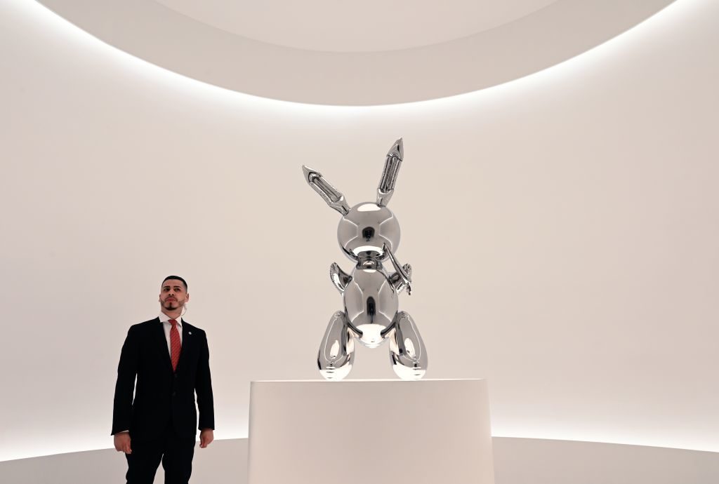 A security guard stands next to Jeff Koons's Rabbit from the 