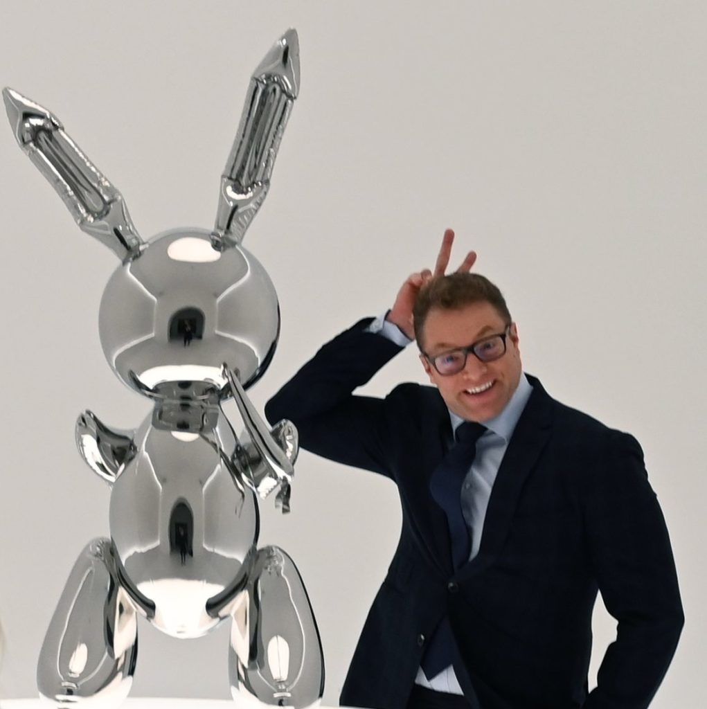 A man poses next to Jeff Koons's Rabbit from the 