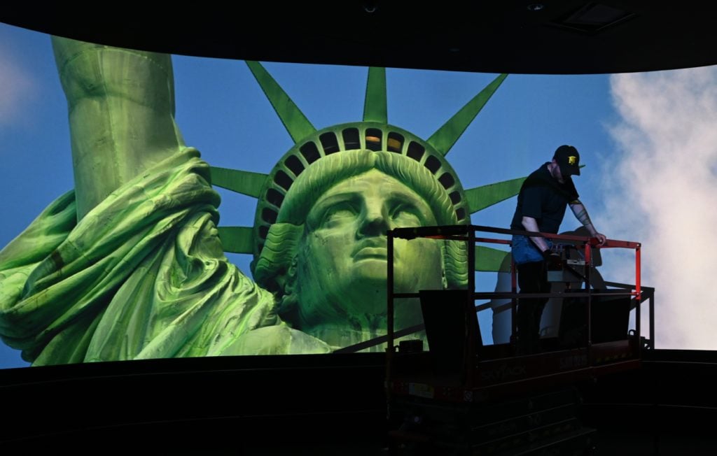 A worker puts finishing touches on the ceiling in a room showing a movie featuring Lady Liberty. Photo by TIMOTHY A. CLARY / AFP/Getty Images.
