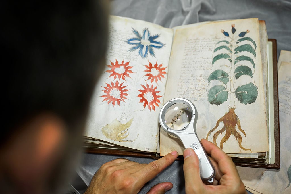 An expert pouring over the Voynich Manuscript in 2016. Photo by Cesar Manso/AFP/Getty Images.