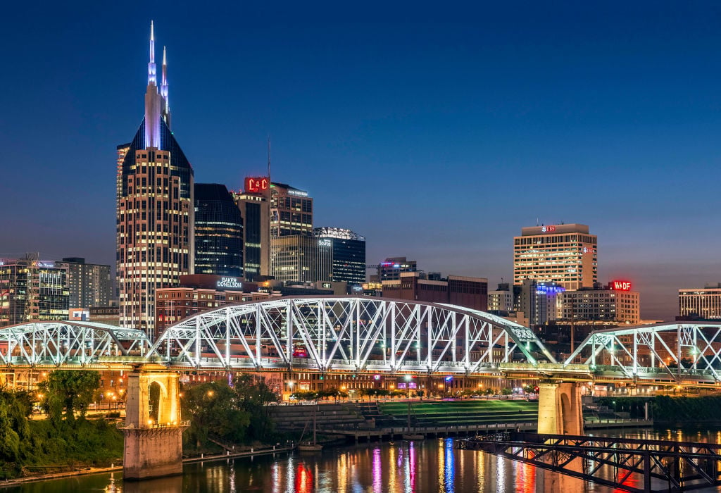 Pedestrian bridge over the Cumberland river and the lights of the Nashville city skyline at dusk. (Photo by John Greim/LightRocket via Getty Images)