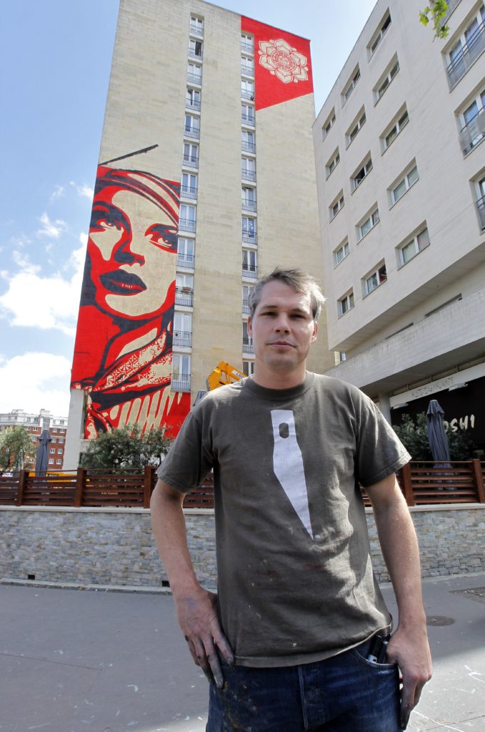 Shepard Fairey poses in front his work in Paris. Photo: Pierre Verdy/AFP/Getty Images.