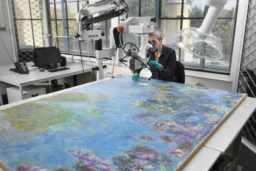 Gemeentemuseum restorer Ruth Hoppe examines Monet's Wisteria painting.