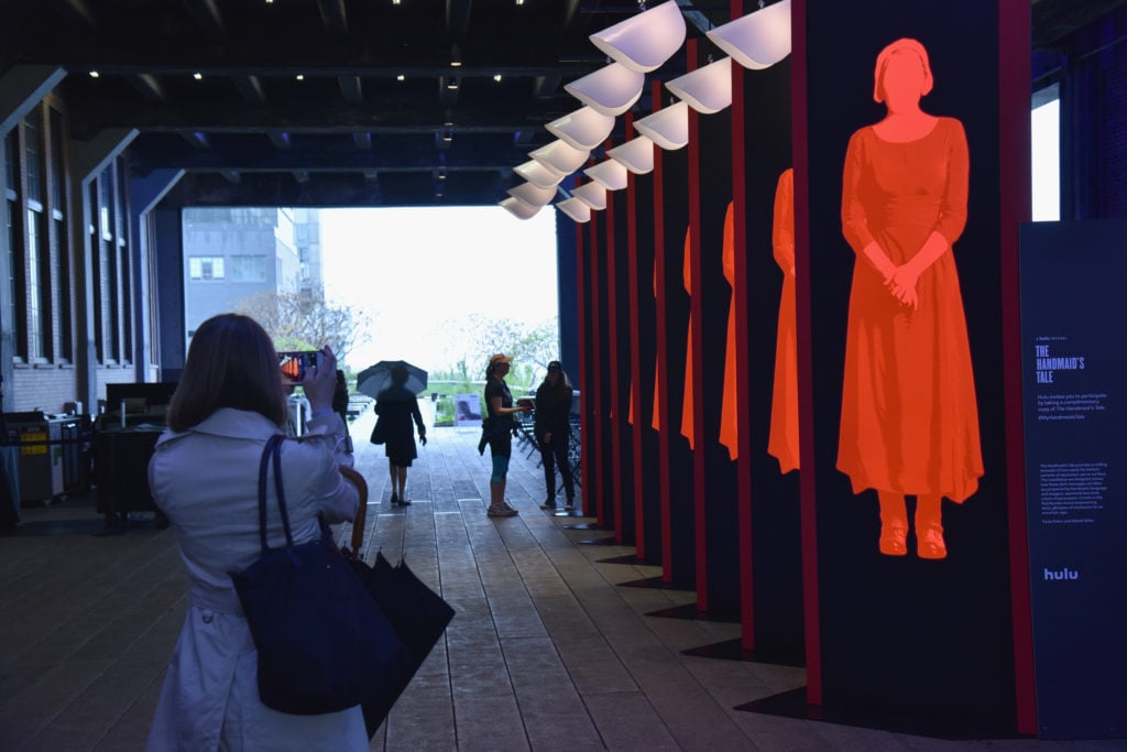 Guest interact with an art installation, designed by Paula Scher and Abbott Miller, and book giveaway celebrating Hulu's </eM>The Handmaid's Tale</em> at the High Line on April 26, 2017 in New York City. Photo by Bryan Bedder/Getty Images for Hulu.