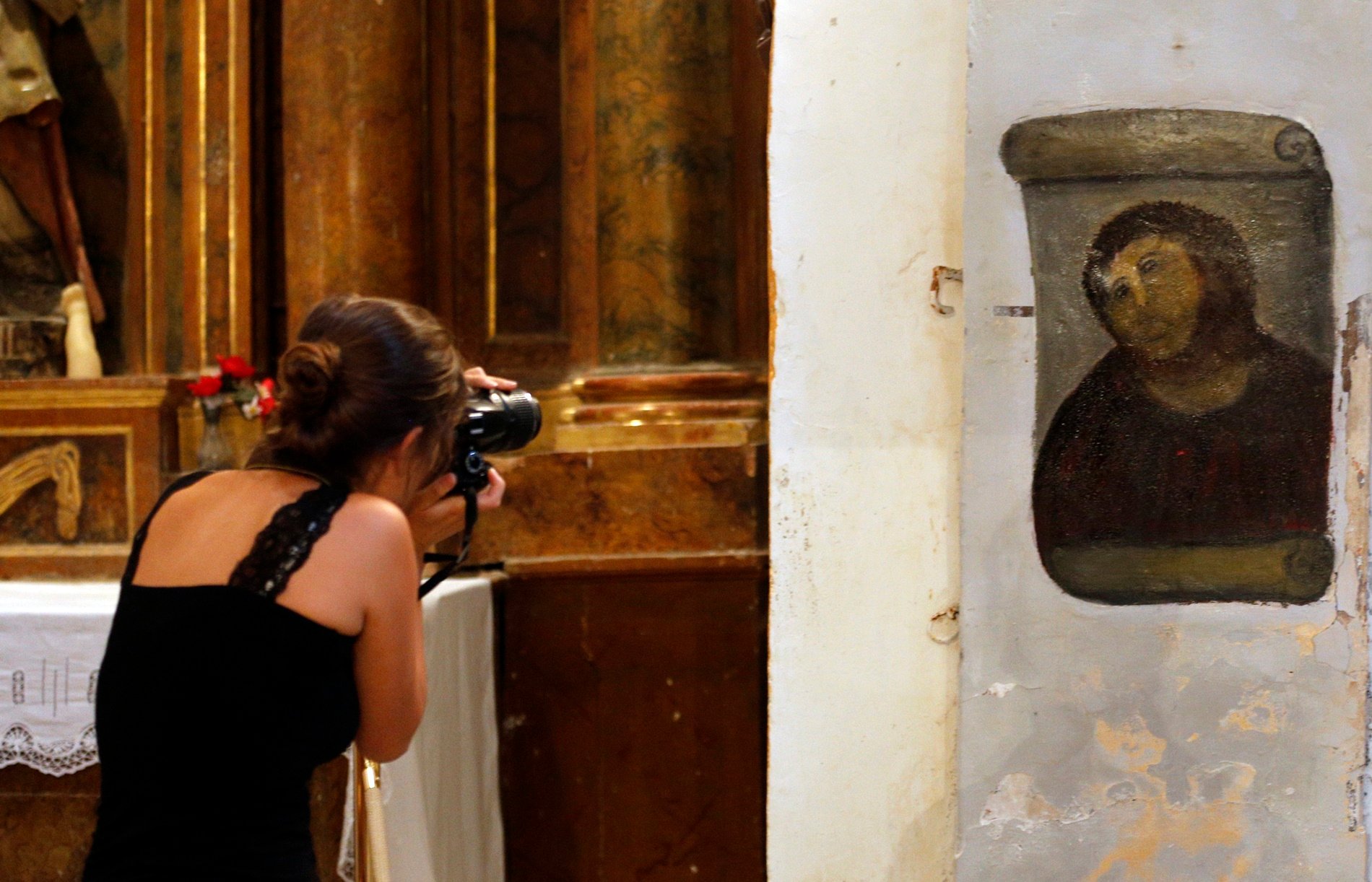 A woman takes pictures of the deteriorated version of "Ecce Homo" by 19th-century painter Elias Garcia Martinez, at the Borja Church in Zaragoza on August 28, 2012. Photo: Cesar Manso/AFP/GettyImages.