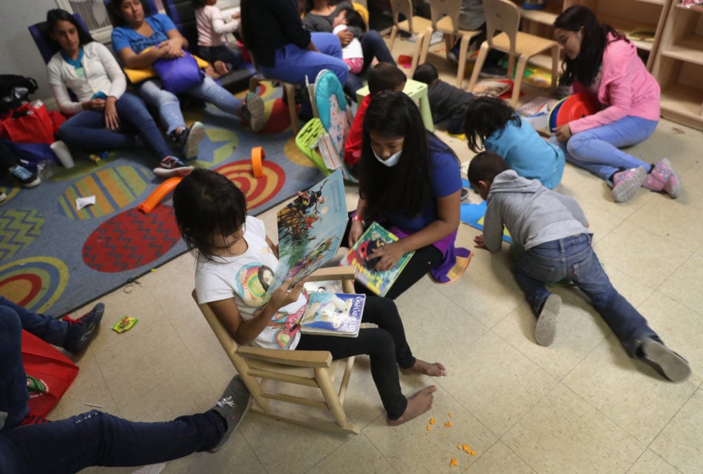 Immigrant families read at an aid center in McAllen, Texas, after being released from US government detention. Photo: John Moore/Getty Images.