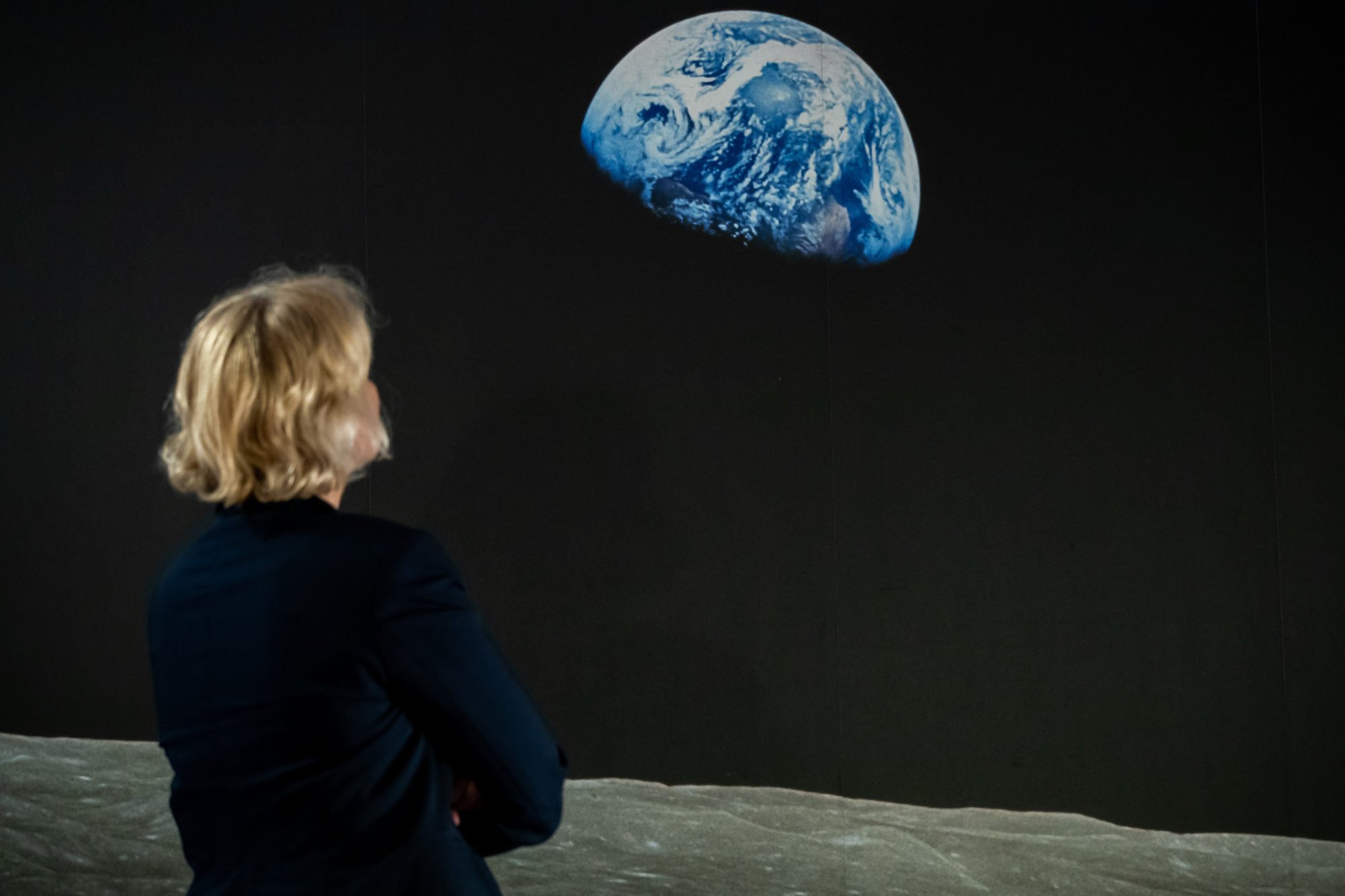 A woman views the "Earthrise" photograph taken from Apollo 8 in an exhibition at the Museum of Communication in Bavaria. Photo by Daniel Karmann/picture alliance via Getty Images