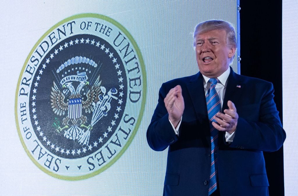 US President Donald Trump stands next to a surreptitiously altered presidential seal as he arrives to address the Turning Point USAs Teen Student Action Summit 2019 in Washington, DC, on July 23, 2019. Photo by Nicholas Kamm/AFP/Getty Images.