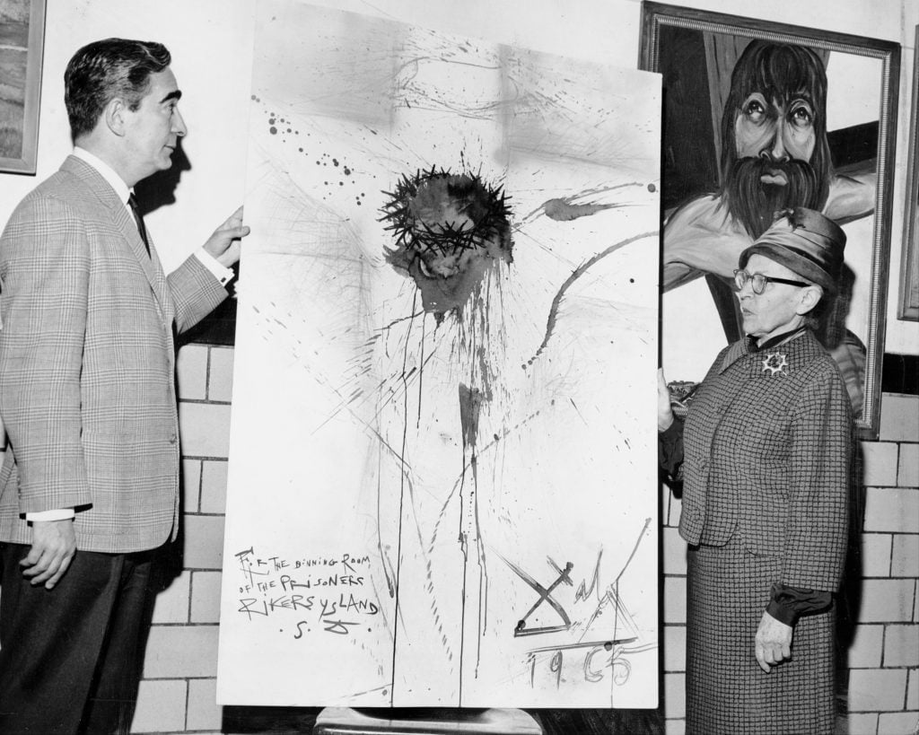 Nico Yperifanos, Salvador Dali's personal representative, presents artist's 'Christ on the Cross" to Rikers Island prison. Correction Commissioner Anna Kross accepts the work. The Dalí painting was stolen by prison guards in 2003. Photo by Leonard Detrick/NY Daily News Archive via Getty Images. 