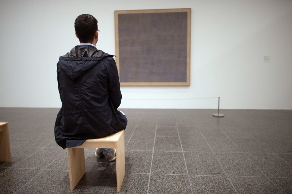 A visitor looks at the picture Falling Blue from 1963 by Agnes Martin in the Kunstsammlung Nordrhein-Westfalen in Duesseldorf, Germany. Photo by Federico Gambarini/picture alliance via Getty Images.