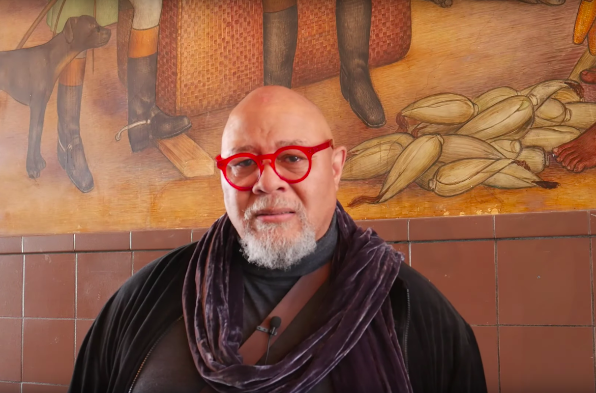 Artist Dewey Crumpler speaking in front of Victor Arnautoff's Life of George Washington murals. Screenshot from YouTube/Artist Dewey Crumpler speaking in front of Victor Arnautoff's Life of George Washington murals. Screenshot from /GWHS Alumni Assn SF CA on YouTube.