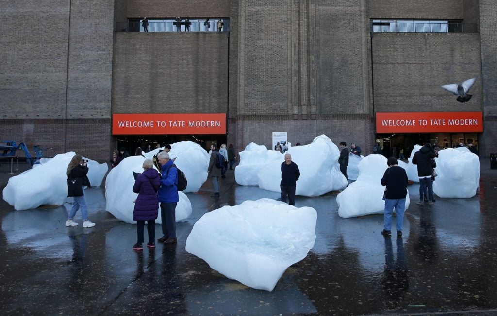 Visitors interact with blocks of melting ice from an exhibit entitled Ice Watch created by Icelandic-Danish artist artist Olafur Eliasson and leading Greenlandic geologist Minik Rosing outside Tate Modern in central London on December 11, 2018. Photo: Daniel Leal-Olivas/AFP/Getty Images.