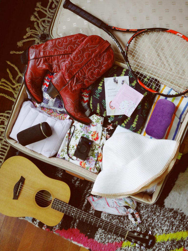Sophie's suitcase featuring camera lenses, cowboy boots, her guitar and tennis racket. Photo courtesy Sophie Elgort.