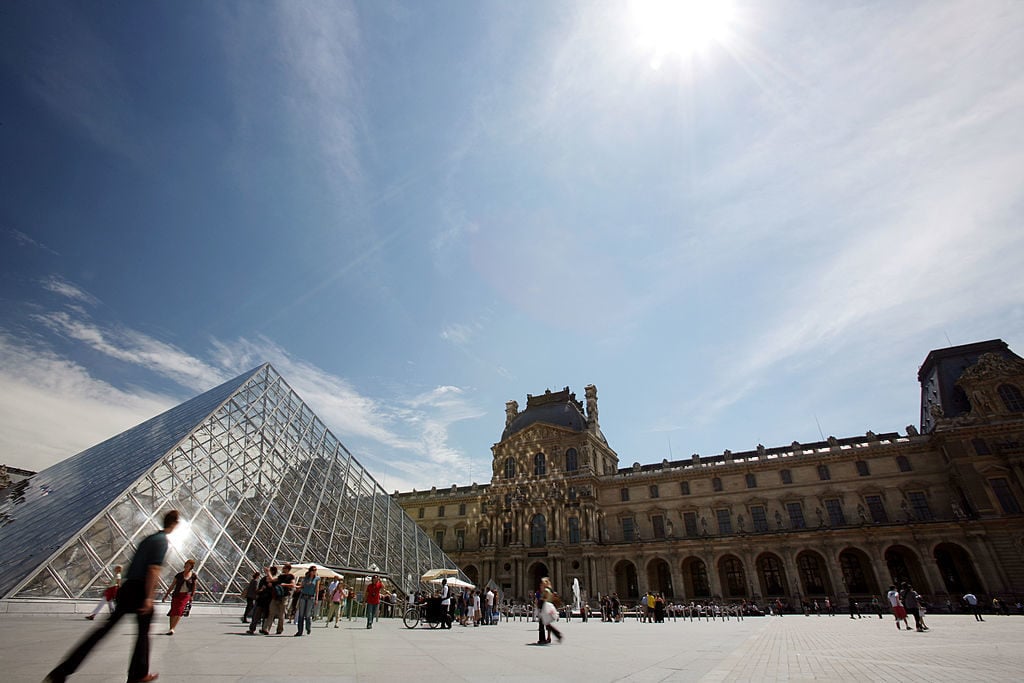 Visitors walk in front of the Pyramid, the entrance of the Louvre Museum. Photo: Loic Venance/AFP/Getty Images.