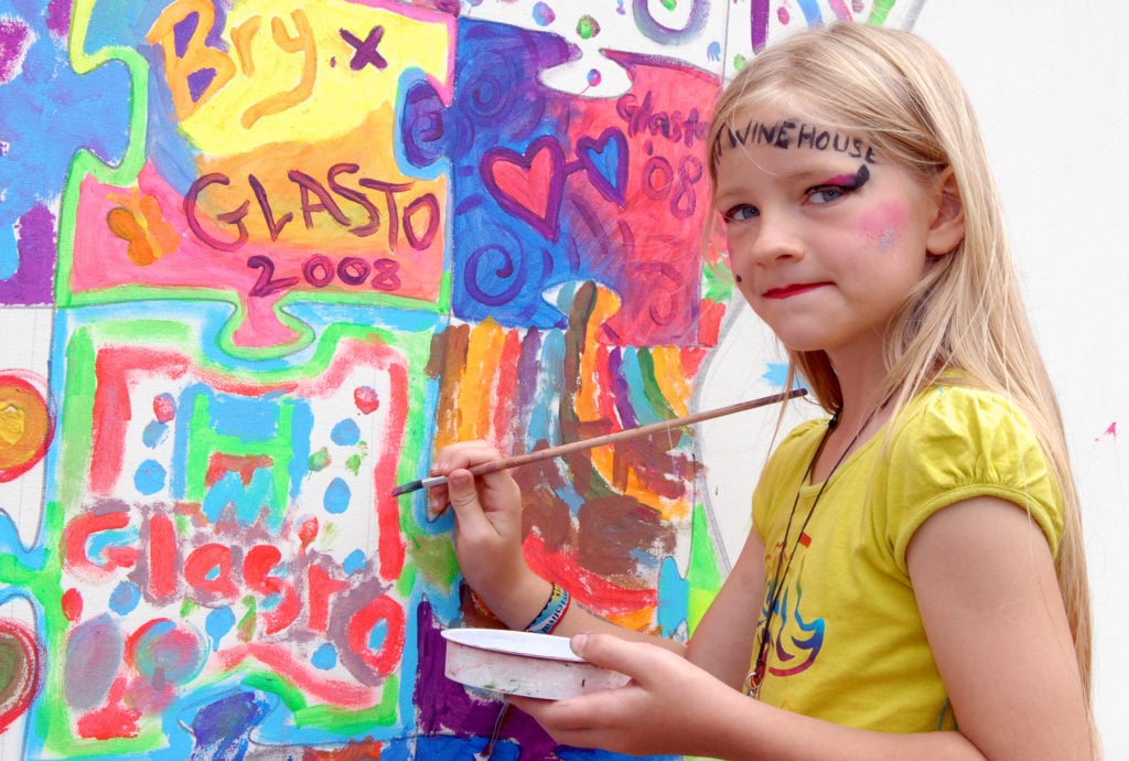 A young girl painting at a local arts festival. Photo: Tabatha Fireman/Redferns/Getty Images.