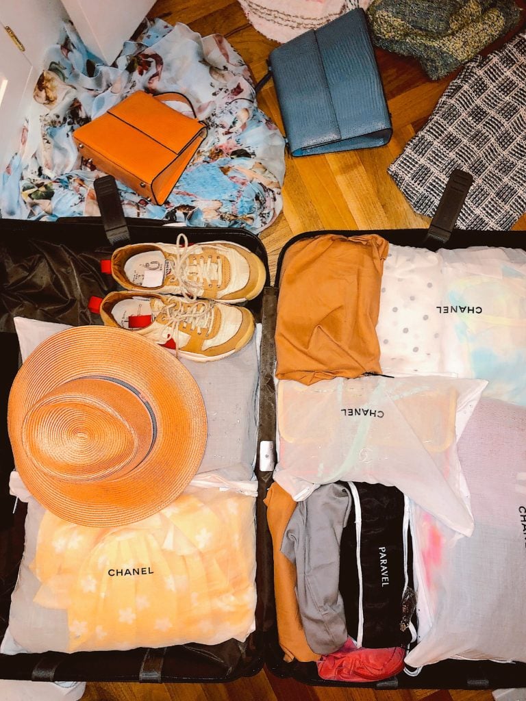 Sarah's suitcase featuring her individually-packed outfits, a panama hat, Nike Mars Yards, and vintage handbags. Photo courtesy Sarah Hoover.