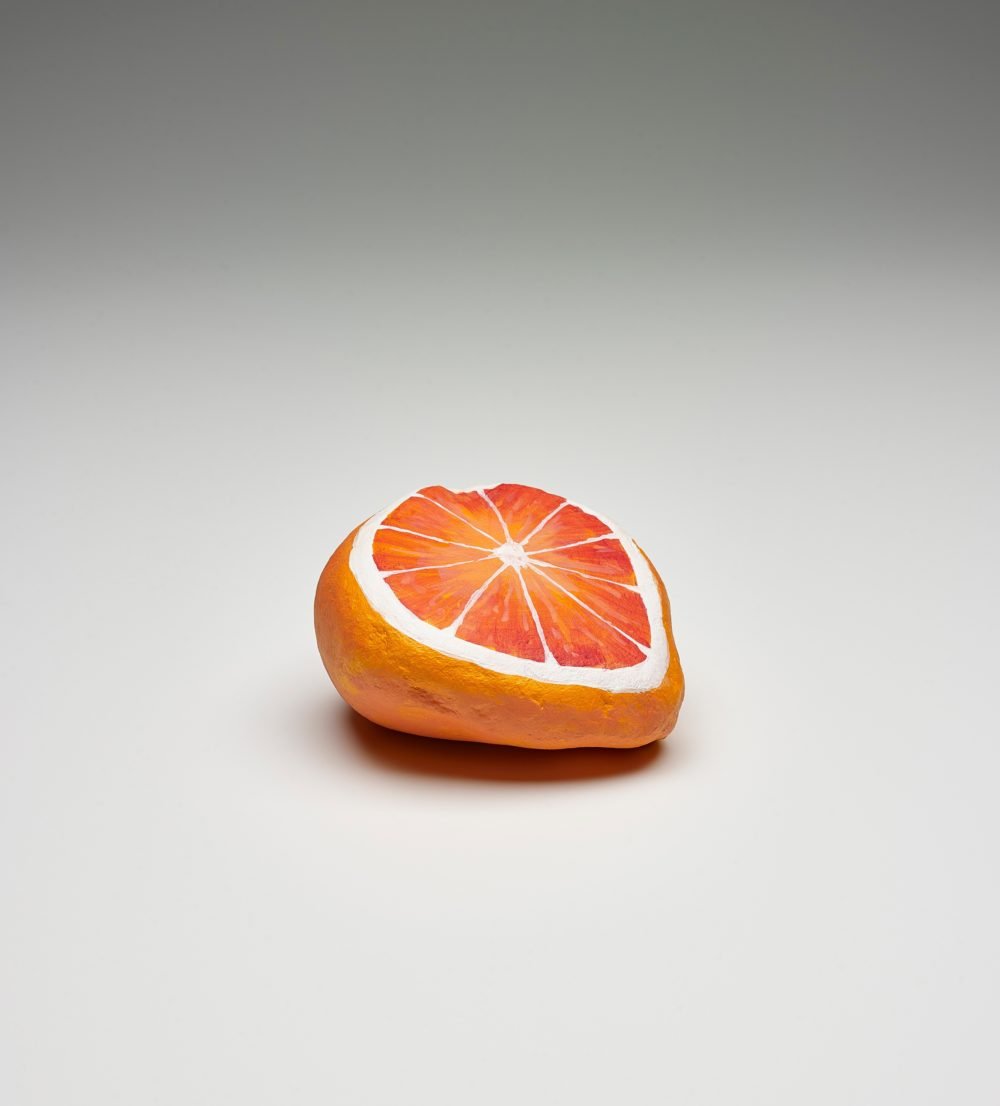 photograph of a stone painted like an orange cut in half