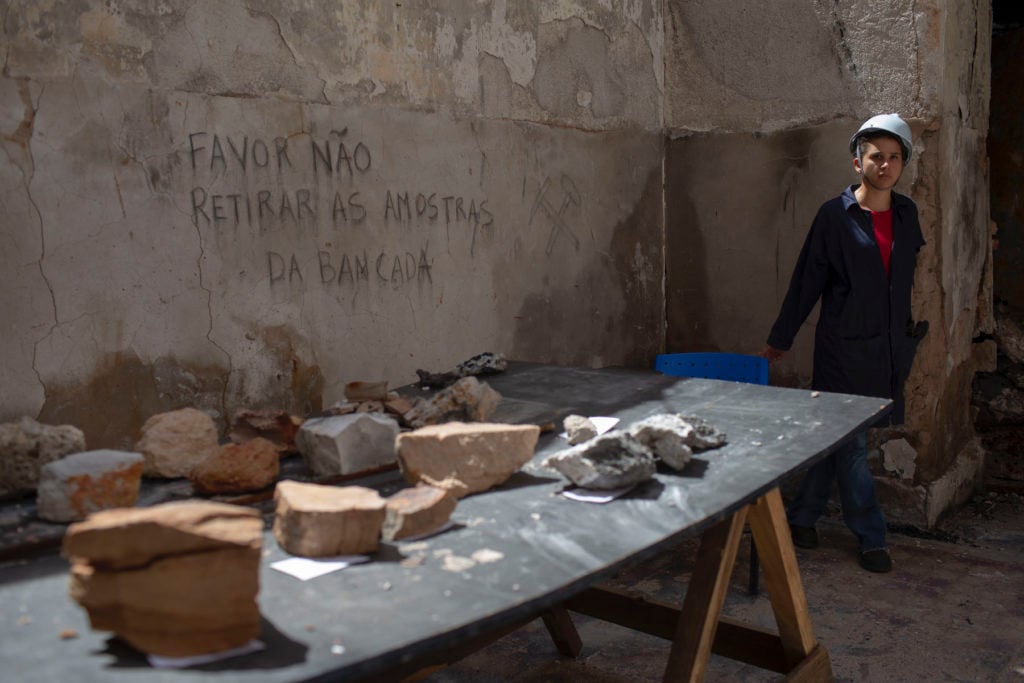 A worker guards artifacts found among the debris inside the National Museum of Brazil. Photo courtesy Mauro Pimentel/AFP/Getty Images.