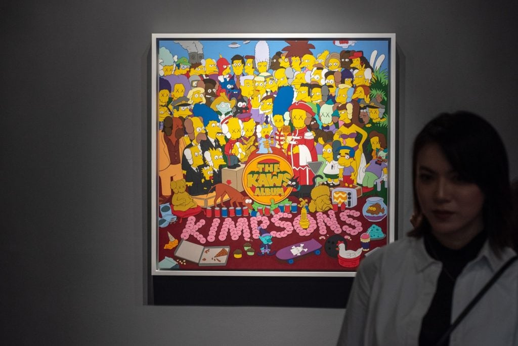 A woman poses for a phtograph in front of US artist KAWS, <em>Untitled (Kimpsons #3)</em> during Sothebys Hong Kong Spring sales media tour in Hong Kong on March 29, 2019. Photo courtesy Philip Fong/AFP/Getty Images.