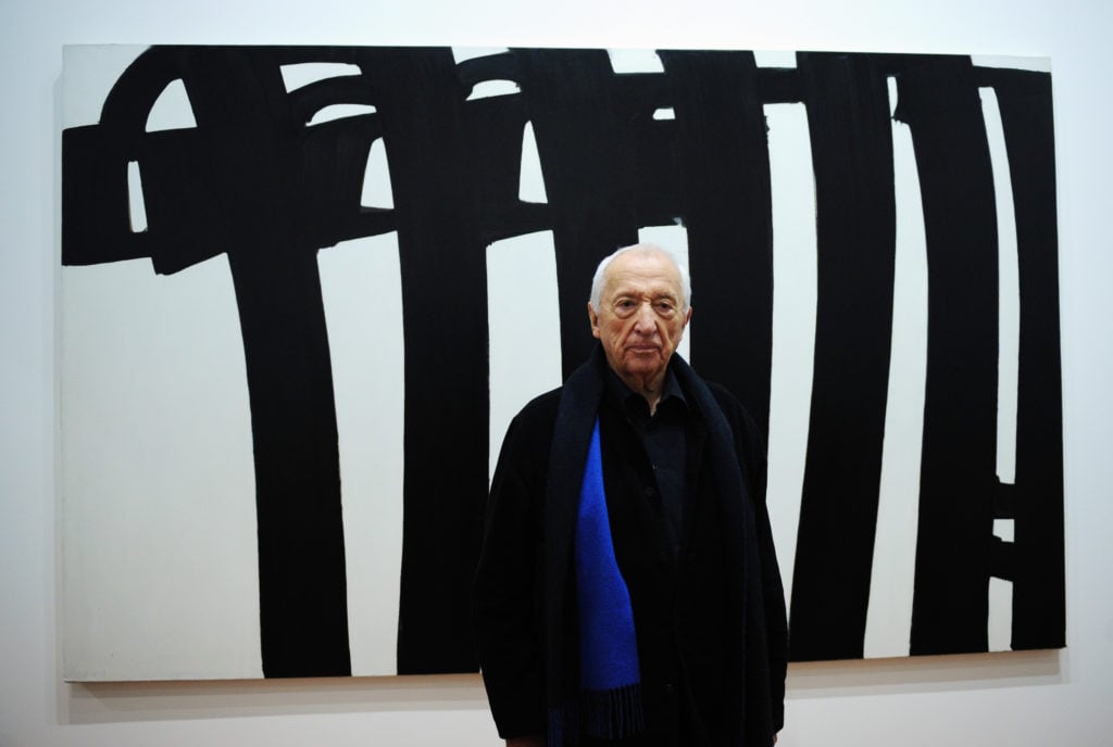 The French abstract painter Pierre Soulages poses in front of one of his paintings during the presentation of his exhibition 